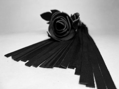 Черная замшевая плеть с лаковой розой в рукояти - 40 см.  Цена 5 608 руб. Длина: 4 см. Восхитительная мини-плеть, украшенная чёрной розой. Цветок полностью выполнен из натуральной лаковой кожи, листочки розы и рукоятка выполнены из мягкой натуральной кожи, а хвосты плети - натуральная мягкая замша. Размеры этой плети очень изящны, поэтому данную плеть можно использовать, как генитальную, чтобы добавить новых ярких ощущений. Розочка очень удобно лежит в руке и создает неповторимую атмосферу и настроение, этот аксессуар никого не оставит равнодушным. Страна: Россия. Материал: натуральная кожа.
